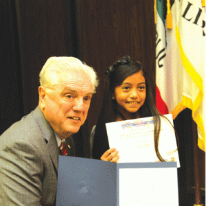 Mayor Mowles presents a certificate to Emily Castro of Escalona Elementary School for First Place in her age group for the 2014 Bookmark Contest.