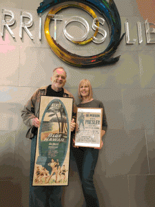 “Mr. Rock N’ Roll”® Brian Beirne and his wife Cindee show off vintage posters of an Elvis Presley film and concert. The posters are part of an exhibition of Beirne's music and movie memorabilia, which are on display at the Cerritos Library through the end of 2016. 