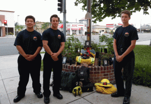 Fire Explorers Johnny Martinez, 15; Brett Corwin, 17; and Alex Hernandez, 15 stand beside the photo, candles and gear that Kevin Woyjeck would have carried.